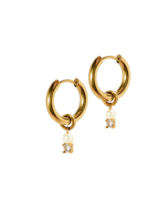 A pair of gold-colored huggie earrings featuring a pearl and a CZ stone hanging from the hoop.