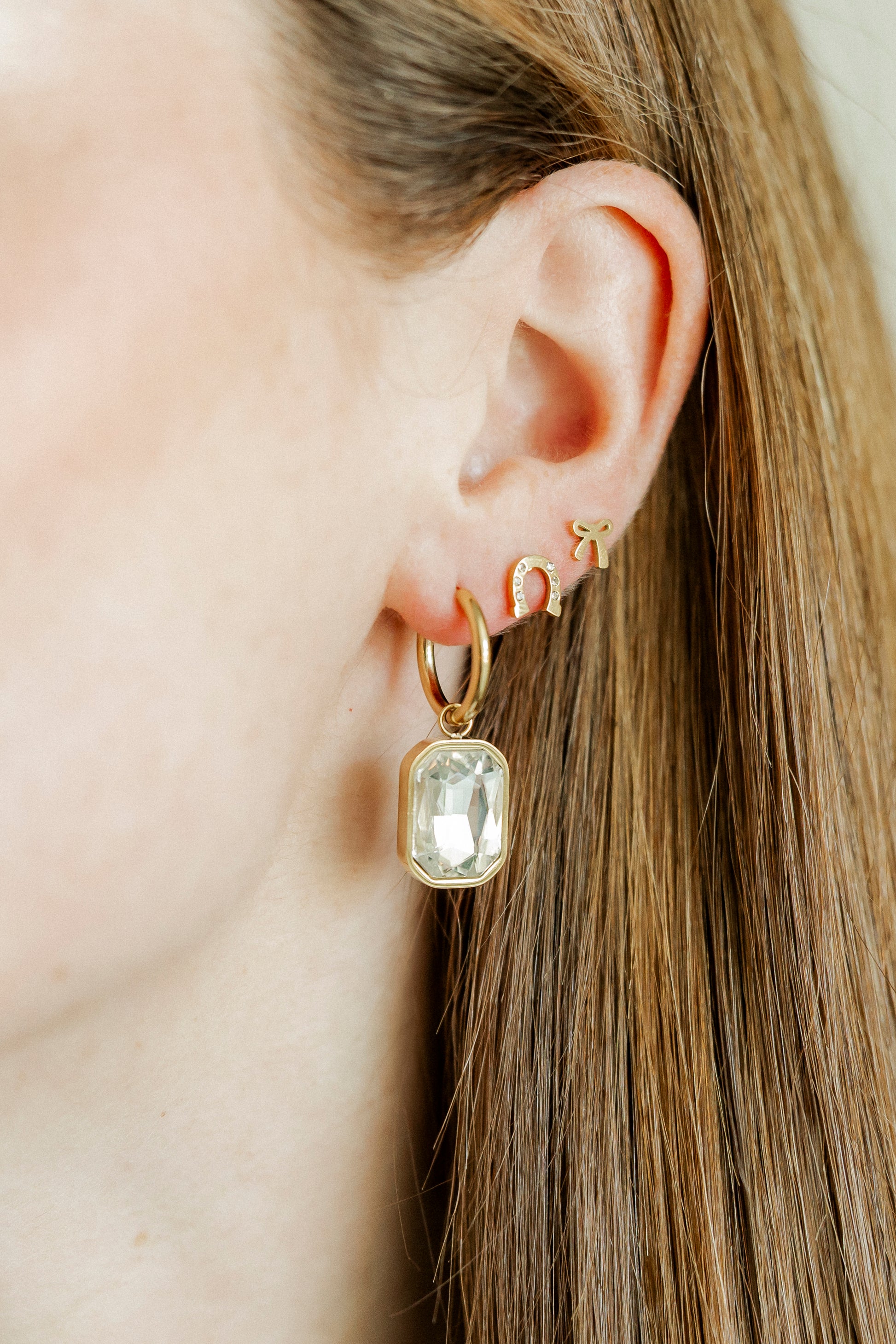 Gold earring with a clear gemstone worn by a person
