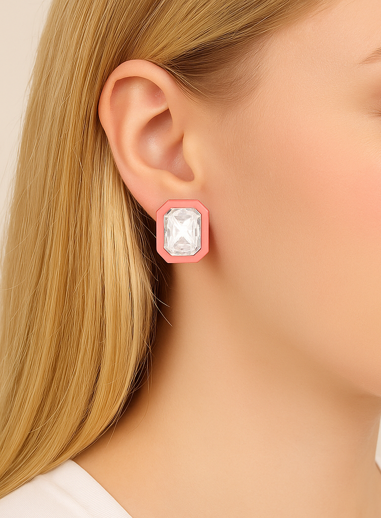 Close-up of a pink earring with a clear gemstone worn by a person.