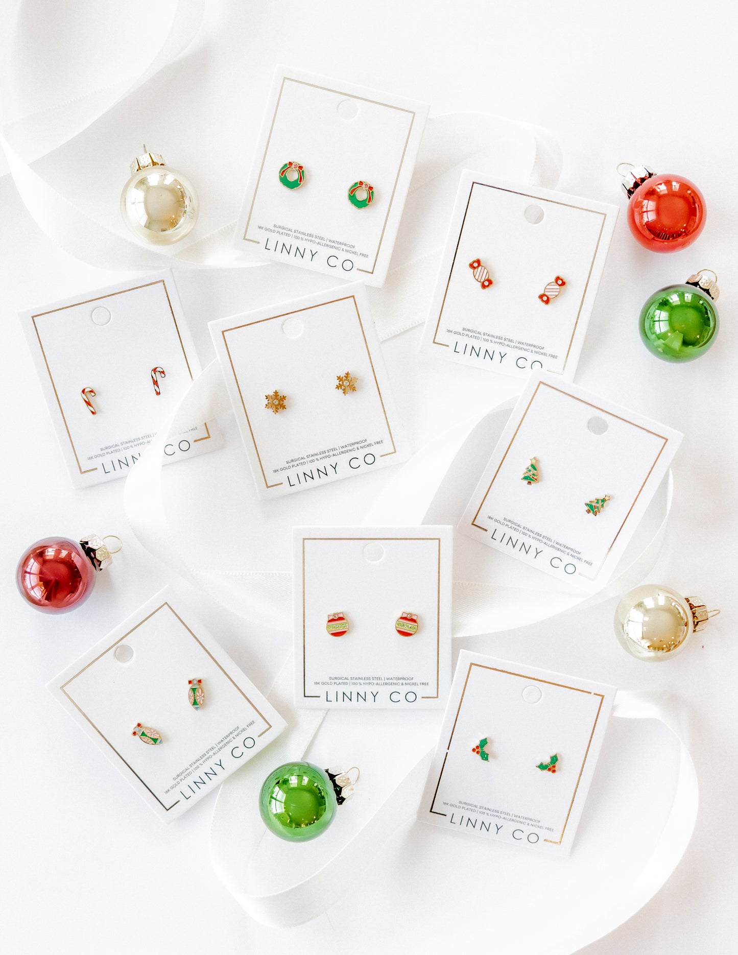 Collection of earrings on LINNY CO cards with Christmas ornaments around