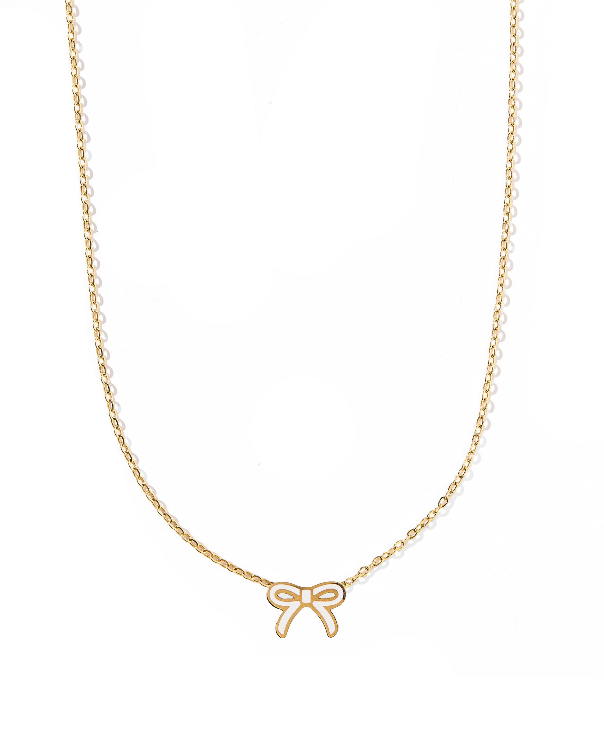 A thin gold bow pendant necklace with a white accent on a white background.