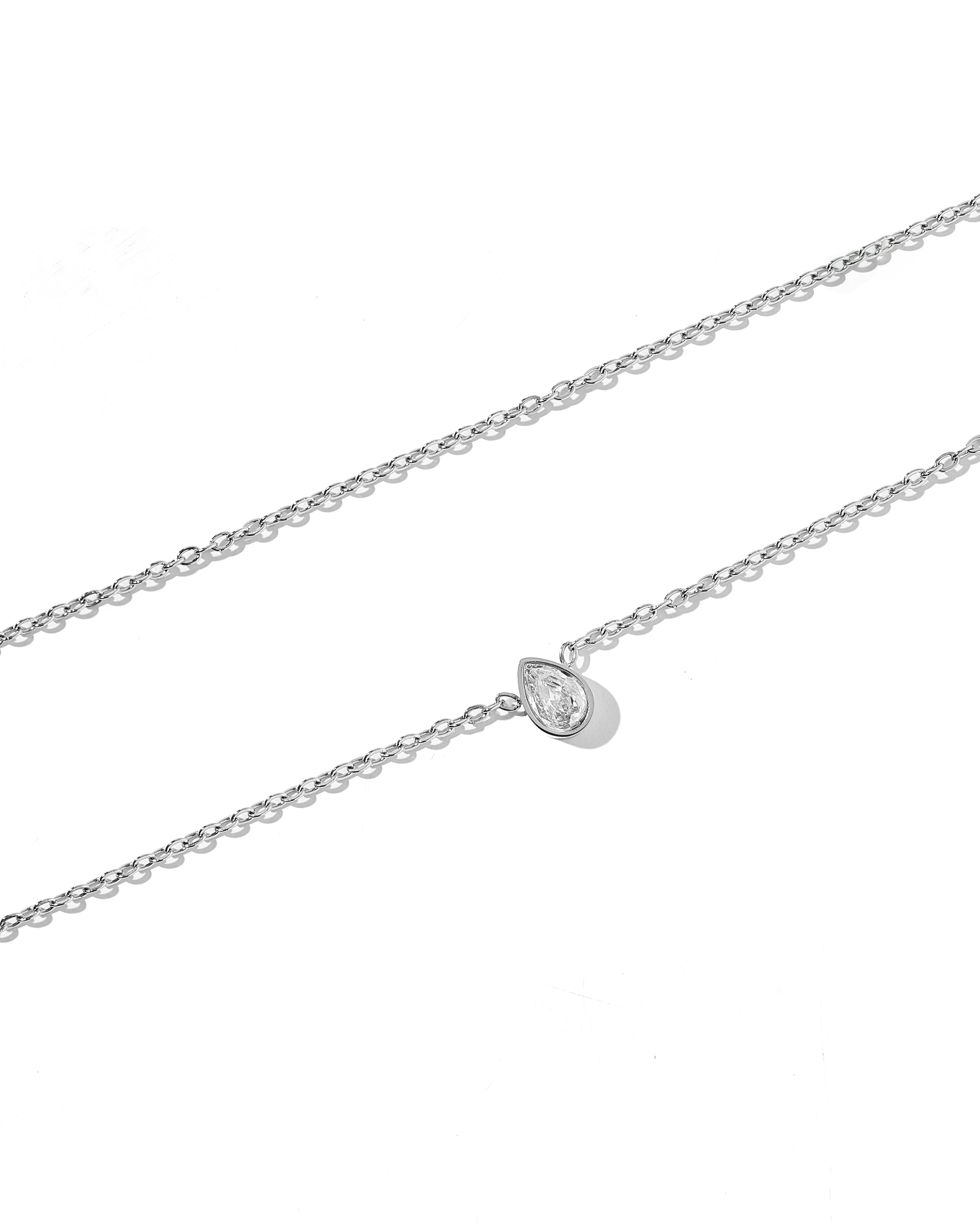 A silver necklace with a pear-shaped clear zirconia stone set in a bezel on a white background.
