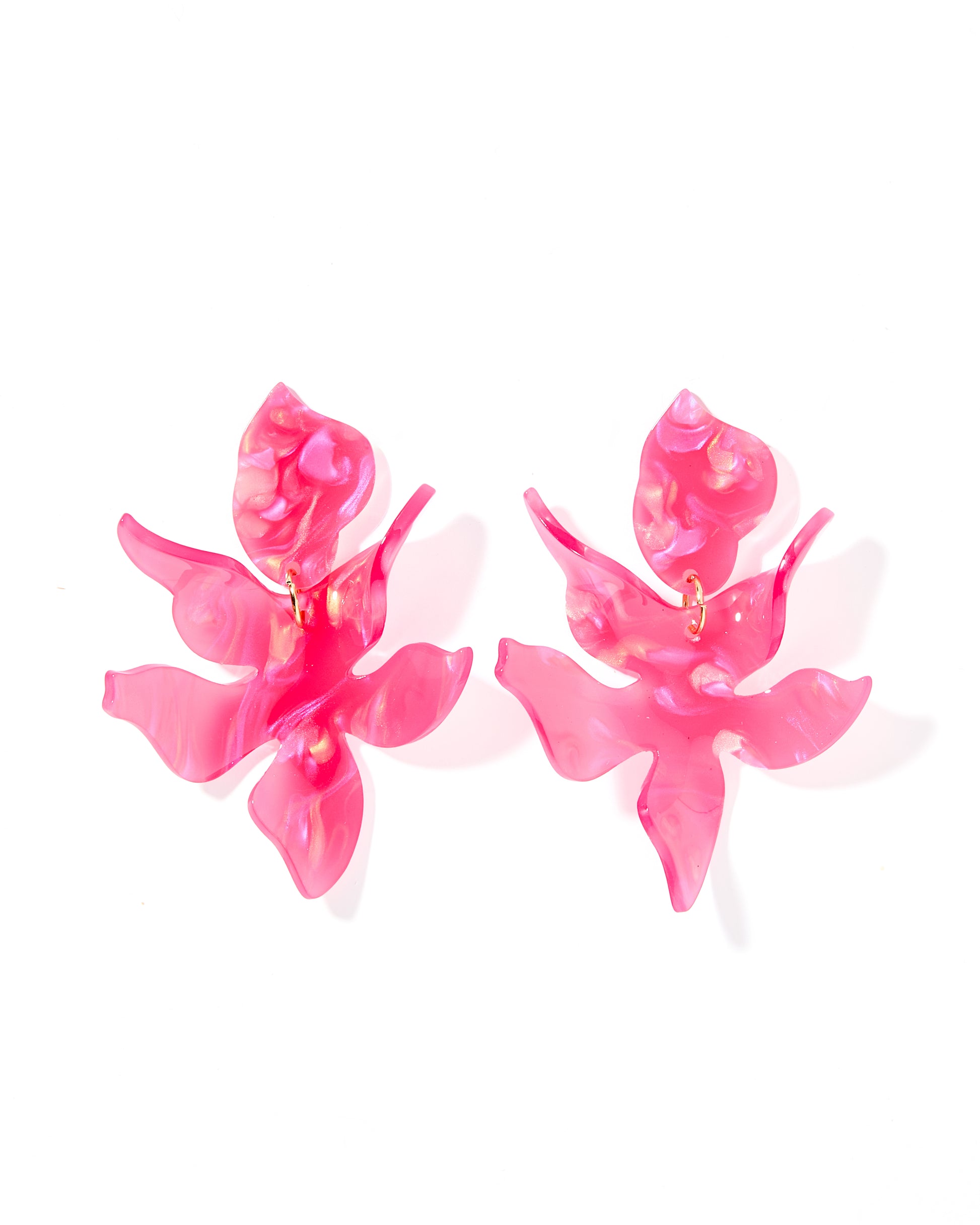 A pair of oversized pink statement earrings with a floral design.