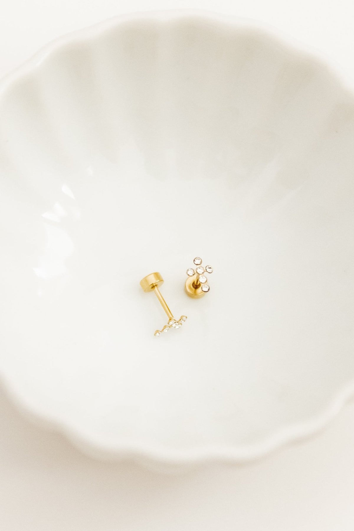 LINNY CO Clara Cross Gold Sparkle screwback stud earrings — hypoallergenic, waterproof stainless steel, flat-lay styling.