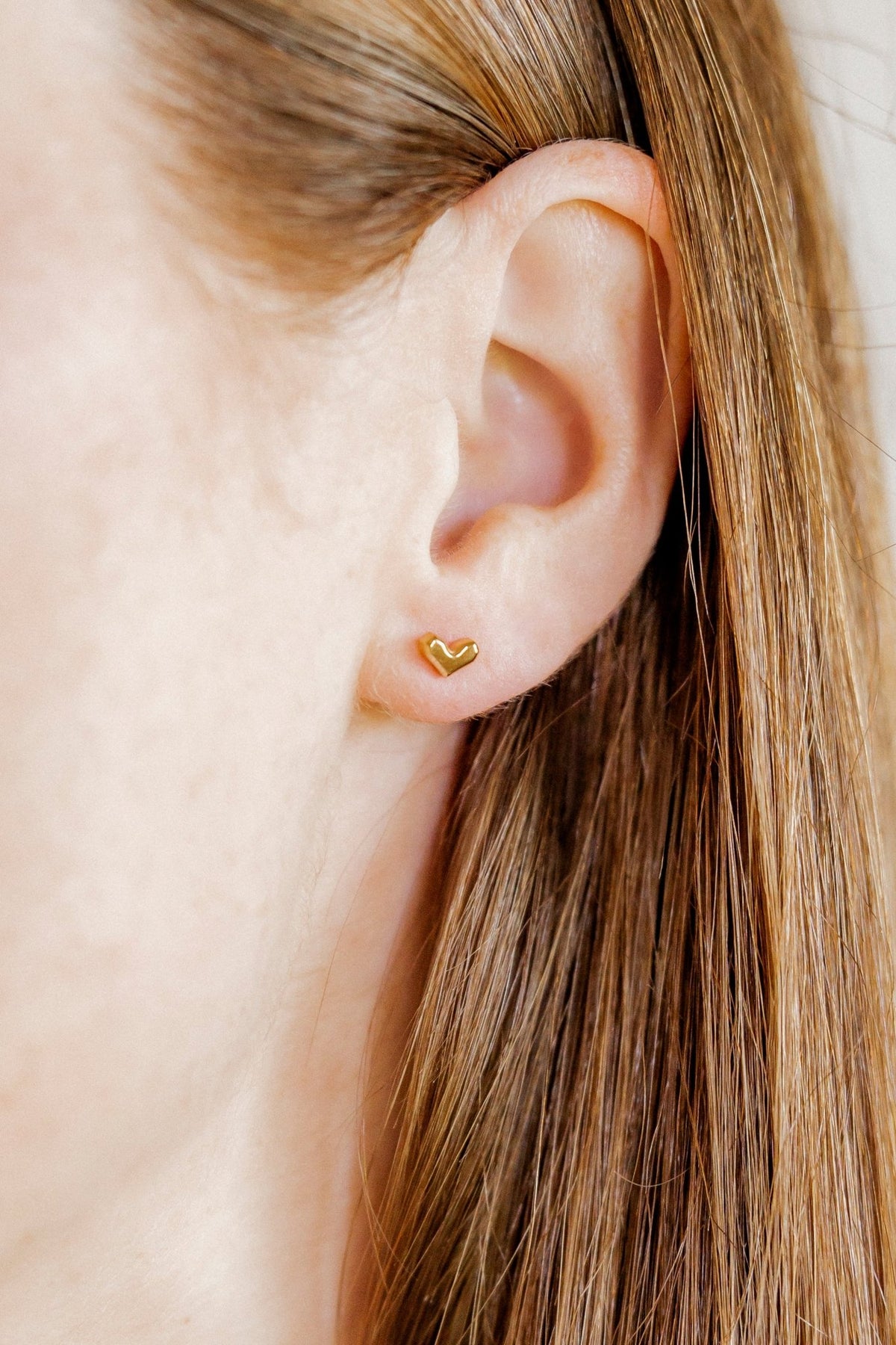 LINNY CO Fable Heart Gold screwback stud earrings for kids & little girls — hypoallergenic, waterproof stainless steel with secure screwback backs, shown on model.