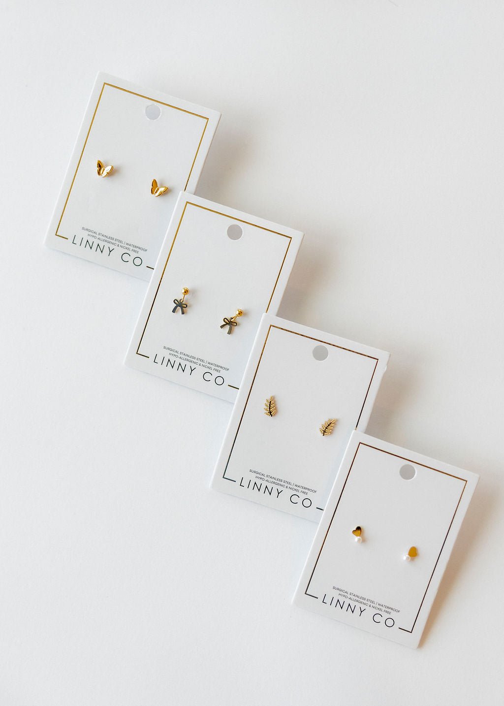 LINNY CO Millie Bow screwback stud earrings for kids & little girls — hypoallergenic, waterproof stainless steel with secure screwback backs, flat-lay styling.