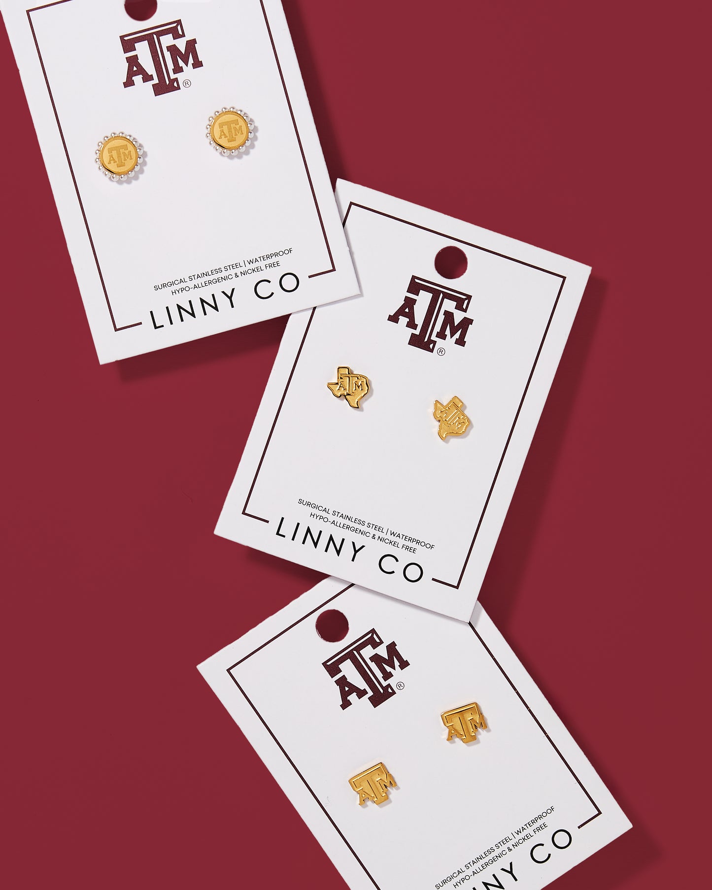 Three pairs of earrings on LINNY CO cards with Texas A&M logo on a red background