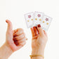 Two hands holding three cards with earrings on a white background