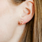 Close-up of an ear wearing a gold hoop earring with hair partially covering the frame.