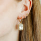 Gold earring with a clear gemstone worn by a person