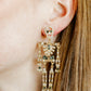 Close-up of a person wearing an ornate earring with green gemstones.