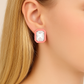 Close-up of a pink earring with a clear gemstone worn by a person.