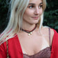 Woman wearing a red cardigan and brown top with a brown rope charm necklace, standing outdoors.