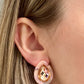 Close-up of a person wearing gold earrings with pink ear cuffs.