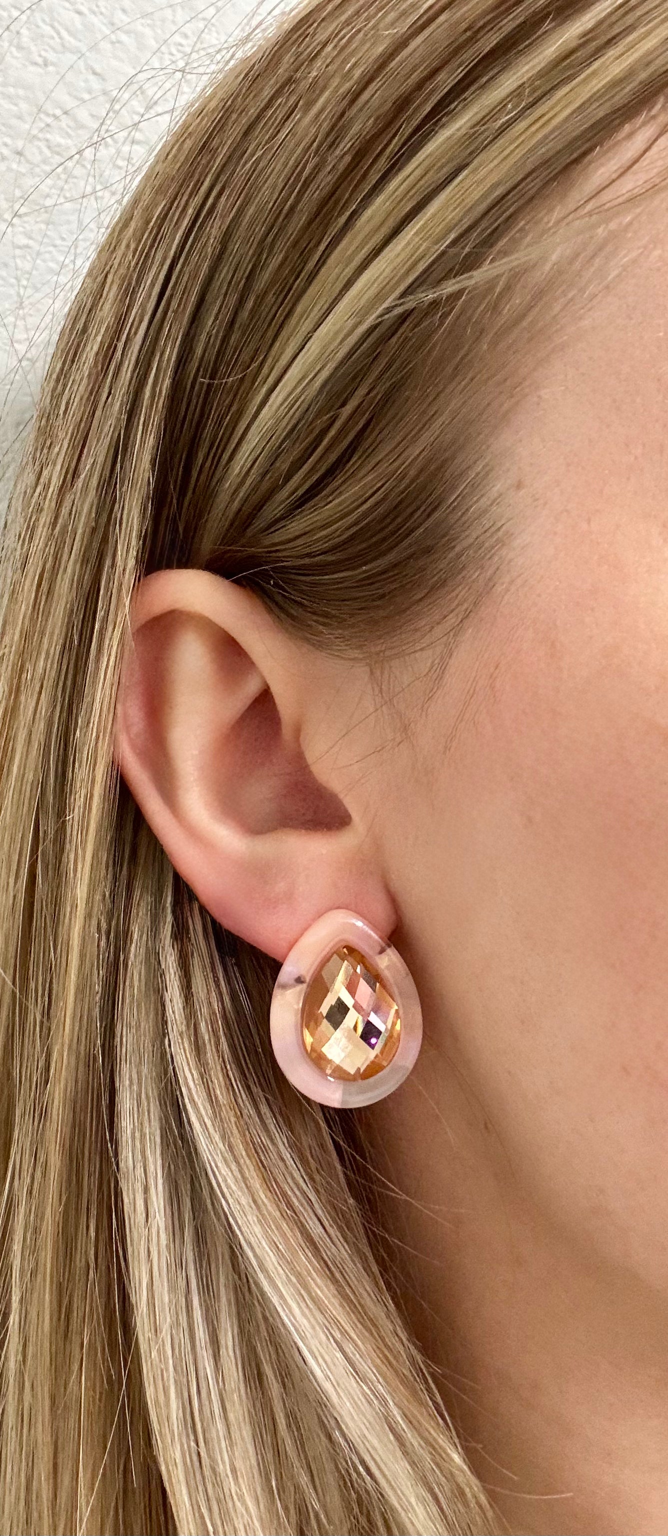 Close-up of a person wearing gold earrings with pink ear cuffs.