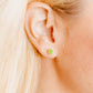 Close-up of a person wearing a small green shamrock earring.