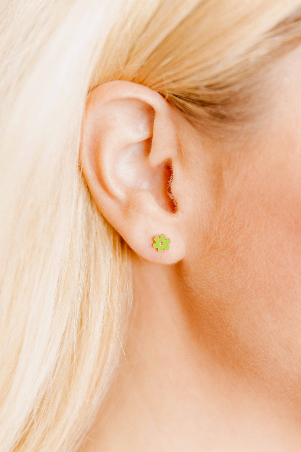 Close-up of a person wearing a small green shamrock earring.