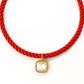 Red rope necklace with a gold and clear pendant on a white background