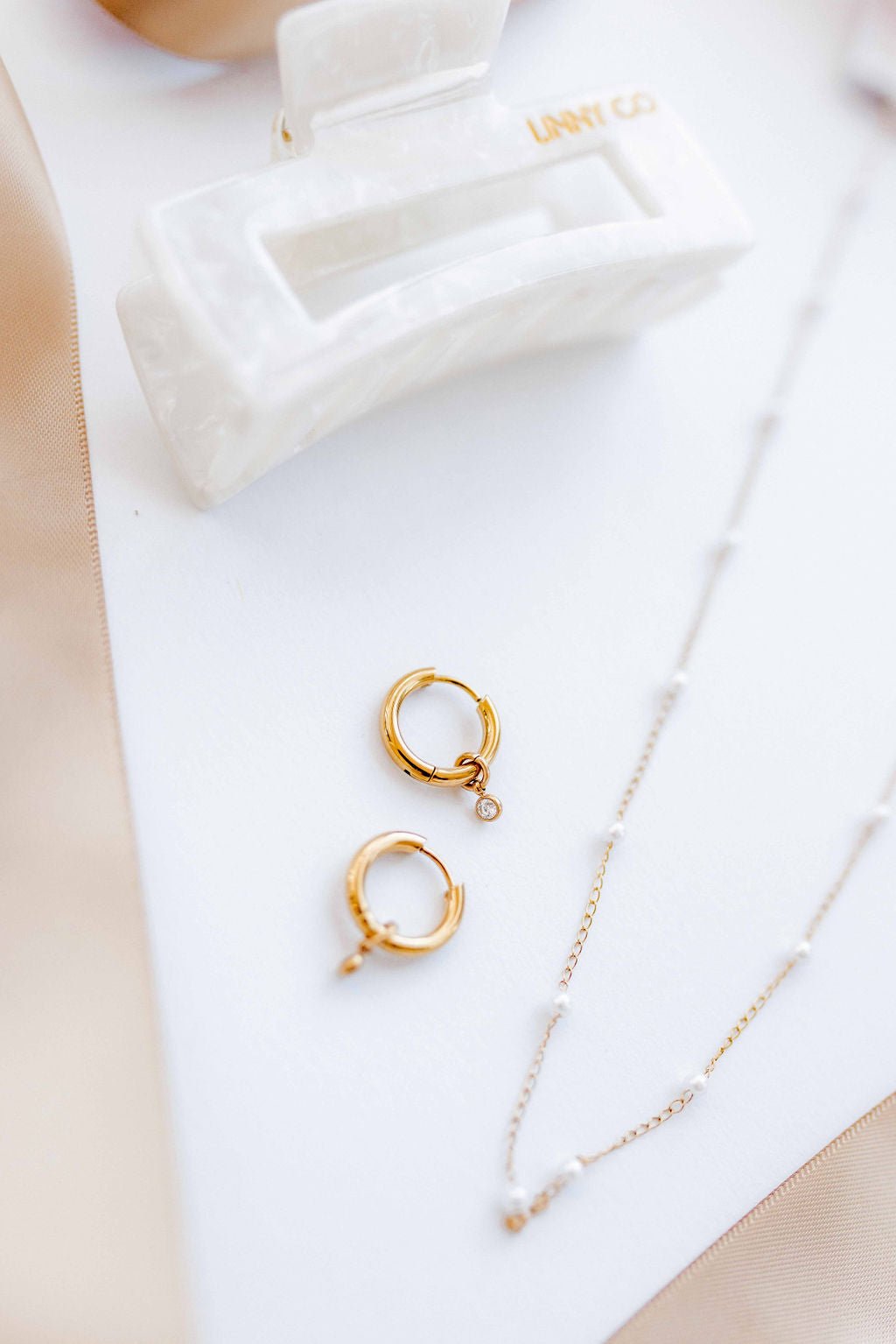 LINNY CO Celine Gold huggie earrings for kids & little girls — hypoallergenic, waterproof stainless steel, flat-lay styling.