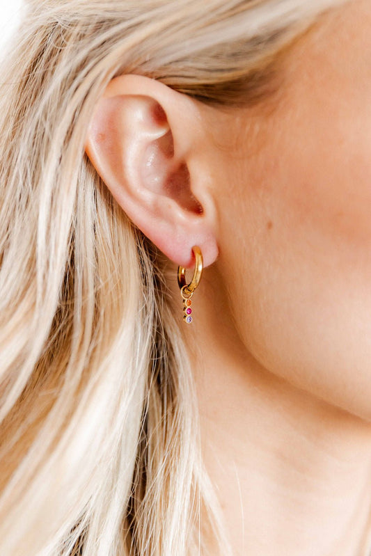LINNY CO Marigold Pink and Purple huggie earrings for kids & little girls — hypoallergenic, waterproof stainless steel, shown on model.