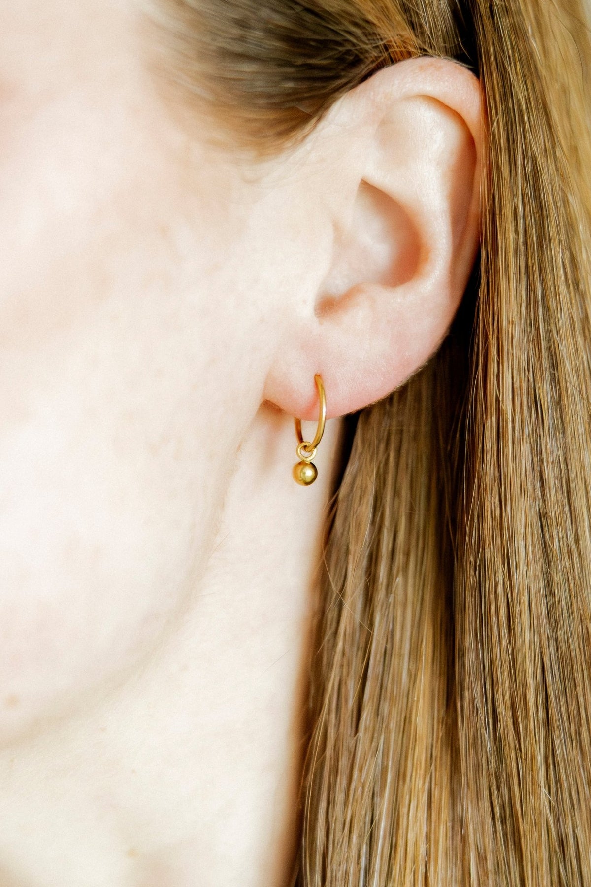LINNY CO Nola 10mm huggie earrings for kids & little girls — hypoallergenic, waterproof stainless steel, shown on model.