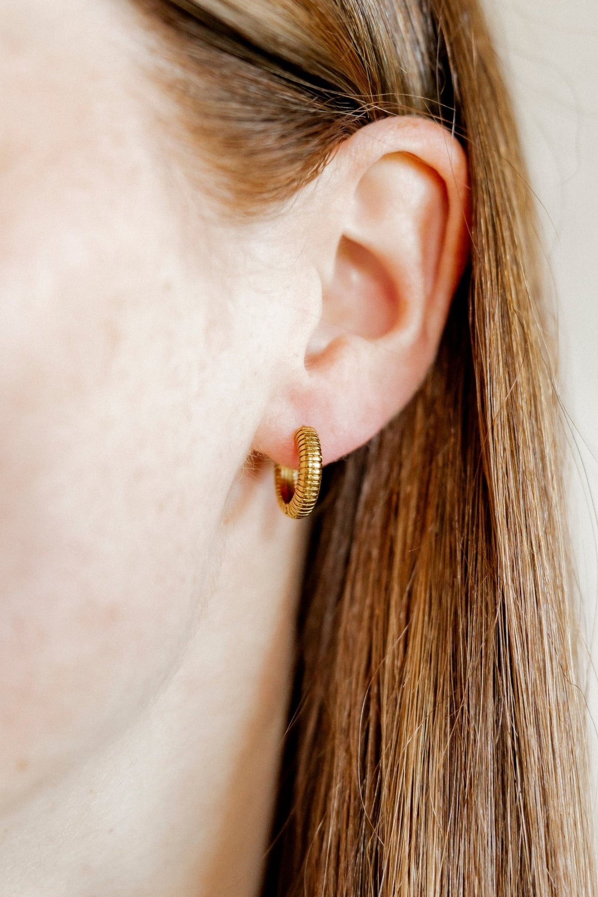 LINNY CO November Gold huggie earrings for kids & little girls — hypoallergenic, waterproof stainless steel, shown on model.