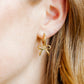LINNY CO Sadie Bow Gold huggie earrings for kids & little girls — hypoallergenic, waterproof stainless steel, shown on model.