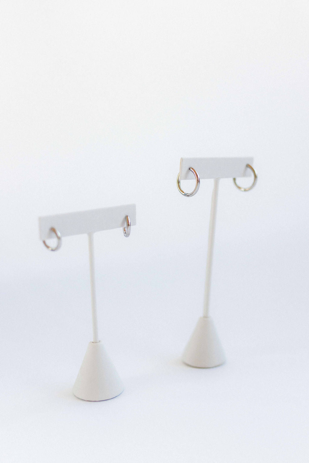 LINNY CO Scarlett Hoop Silver 10mm huggie earrings for kids & little girls — hypoallergenic, waterproof stainless steel, flat-lay styling.