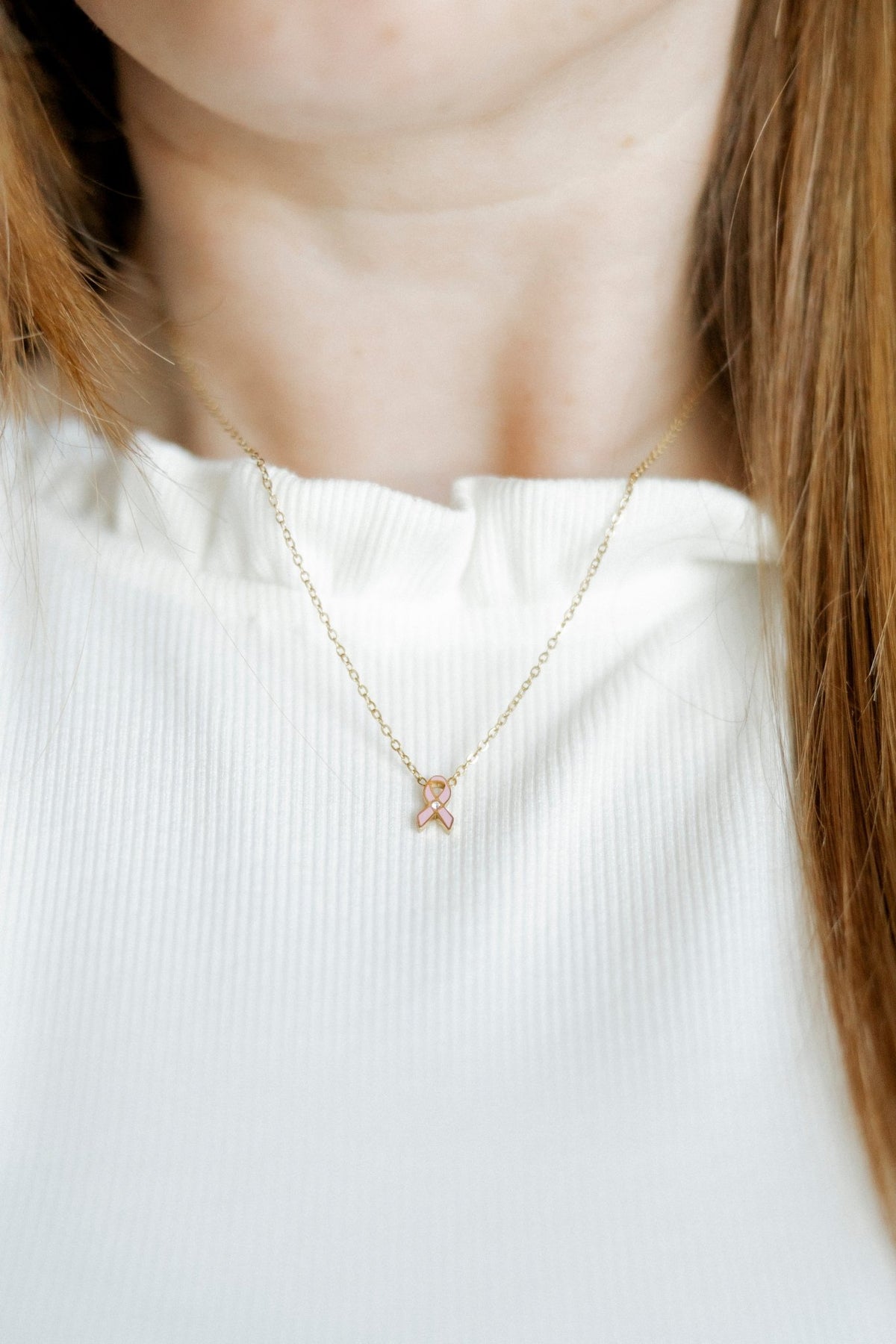 LINNY CO Breast Cancer Ribbon necklace for kids & little girls — hypoallergenic, waterproof stainless steel, shown on model.