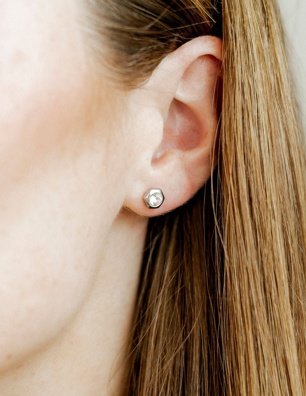 LINNY CO Addison Clear Silver screwback stud earrings for kids & little girls — hypoallergenic, waterproof stainless steel with secure screwback backs, shown on model.