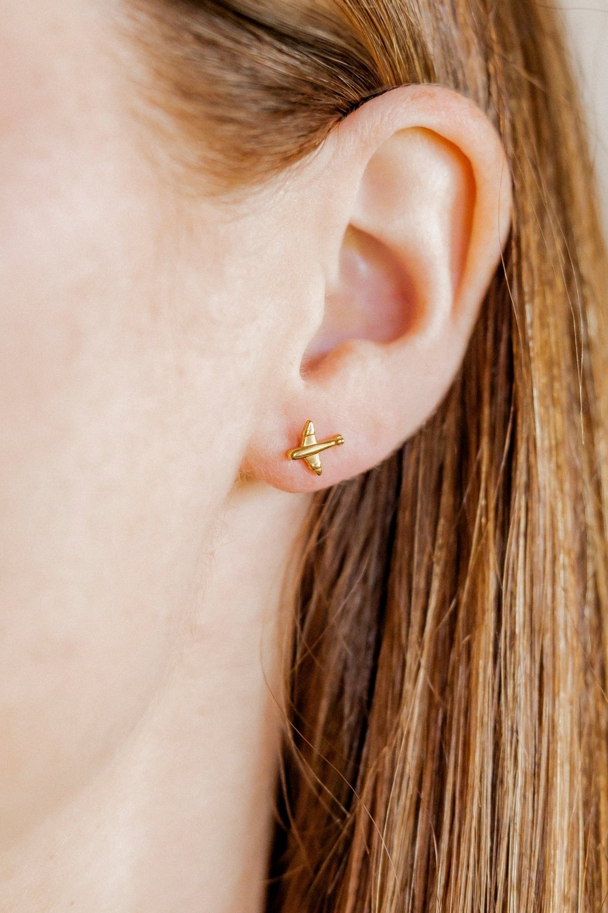 LINNY CO Airplane Gold screwback stud earrings for kids & little girls — hypoallergenic, waterproof stainless steel with secure screwback backs, shown on model.