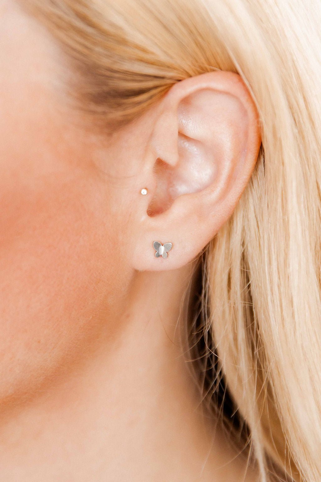 LINNY CO Billie Butterfly Silver screwback stud earrings for kids & little girls — hypoallergenic, waterproof stainless steel with secure screwback backs, shown on model.