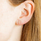 LINNY CO Clara Cross Gold Sparkle screwback stud earrings — hypoallergenic, waterproof stainless steel, shown on model.