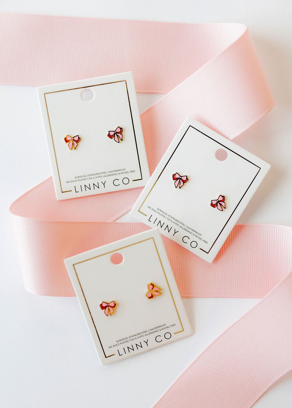 LINNY CO Collins Bow screwback stud earrings for kids & little girls — hypoallergenic, waterproof stainless steel with secure screwback backs, flat-lay styling.