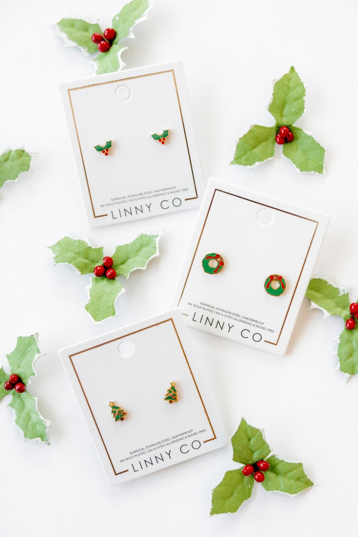 LINNY CO Holly Berry screwback stud earrings for kids & little girls — hypoallergenic, waterproof stainless steel with secure screwback backs, flat-lay styling.