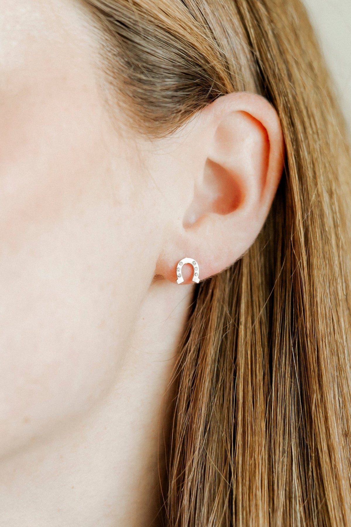 LINNY CO Horseshoe Silver screwback stud earrings for kids & little girls — hypoallergenic, waterproof stainless steel with secure screwback backs, shown on model.