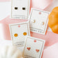 LINNY CO Knox Pumpkin screwback stud earrings for kids & little girls — hypoallergenic, waterproof stainless steel with secure screwback backs, flat-lay styling.