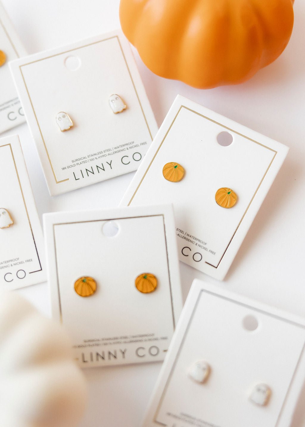 LINNY CO Knox Pumpkin screwback stud earrings for kids & little girls — hypoallergenic, waterproof stainless steel with secure screwback backs, flat-lay styling.