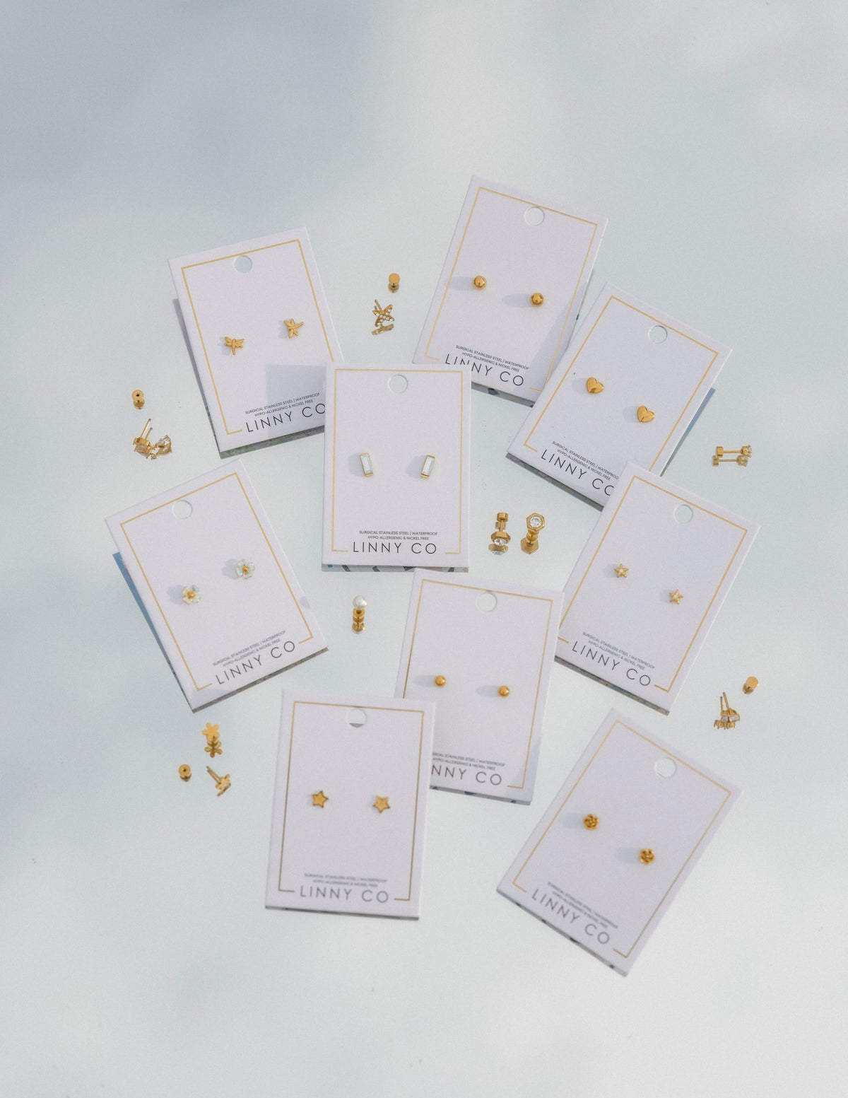 LINNY CO Lennon Star Gold screwback stud earrings for kids & little girls — hypoallergenic, waterproof stainless steel with secure screwback backs, flat-lay styling.