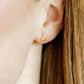 LINNY CO Micro Christmas Tree screwback stud earrings for kids & little girls — hypoallergenic, waterproof stainless steel with secure screwback backs, shown on model.