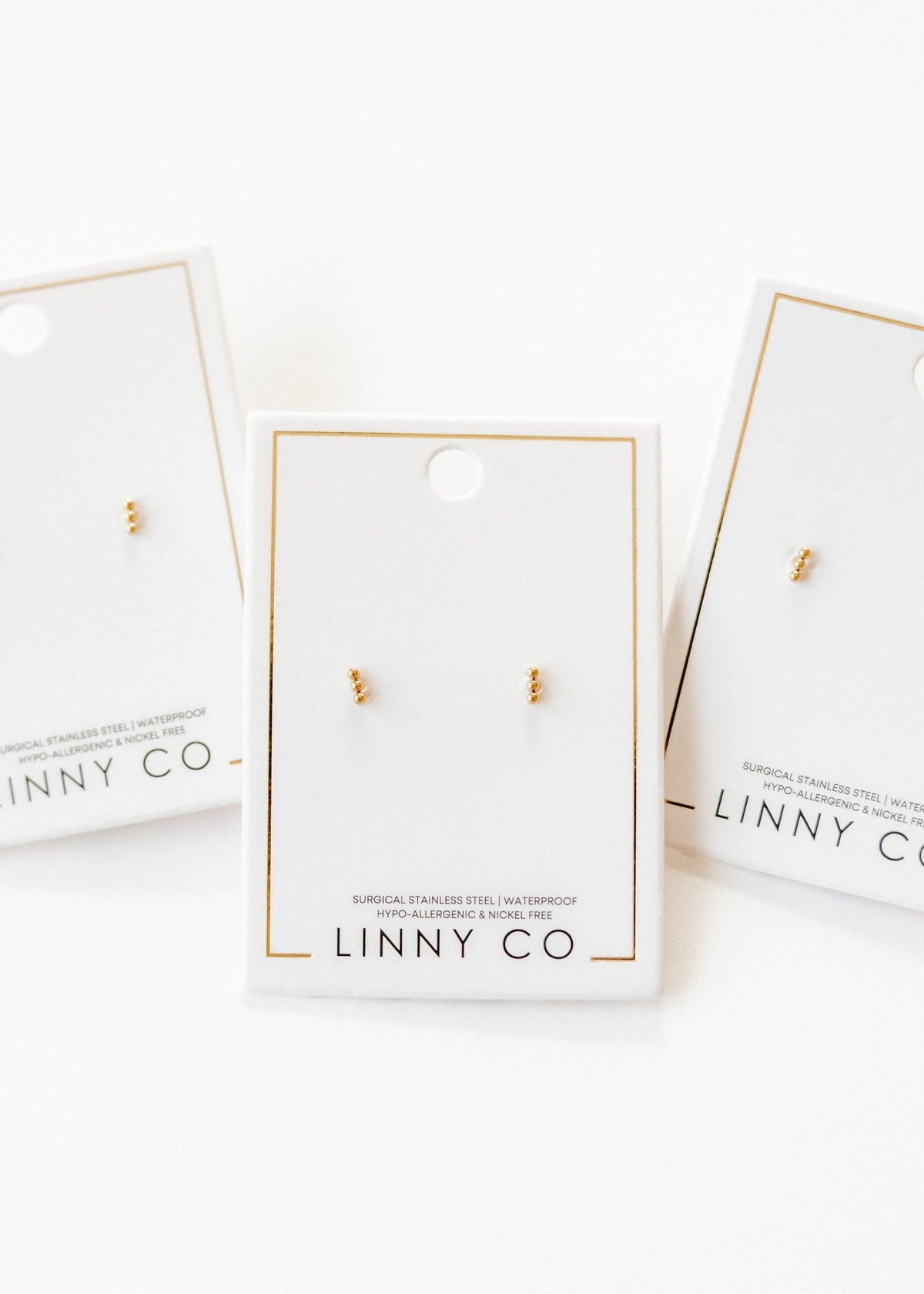 LINNY CO Micro Tally Gold screwback stud earrings for kids & little girls — hypoallergenic, waterproof stainless steel with secure screwback backs, flat-lay styling.