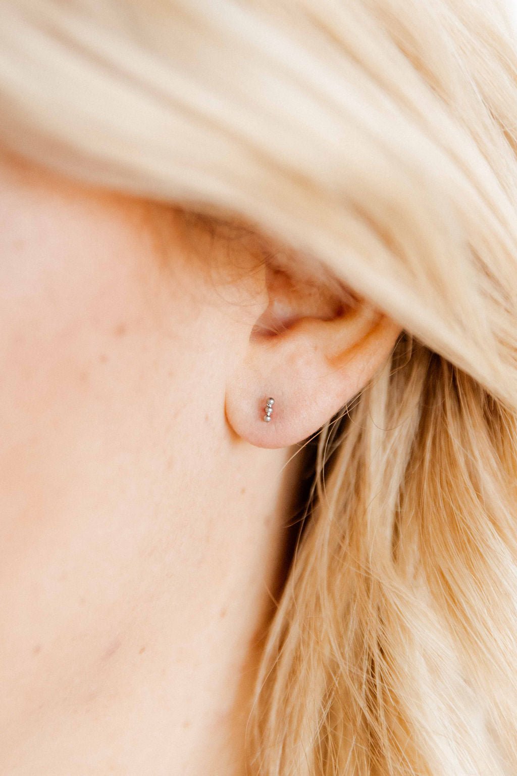 LINNY CO Micro Tally Silver screwback stud earrings for kids & little girls — hypoallergenic, waterproof stainless steel with secure screwback backs, shown on model.