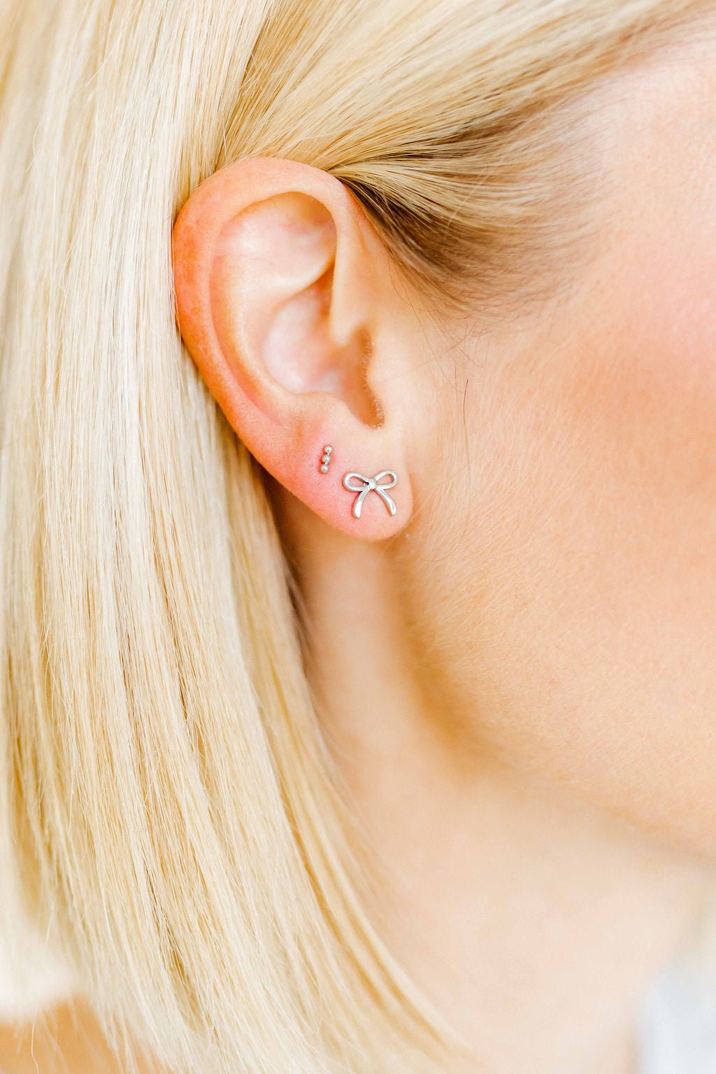 LINNY CO Micro Tally Silver screwback stud earrings for kids & little girls — hypoallergenic, waterproof stainless steel with secure screwback backs, shown on model.