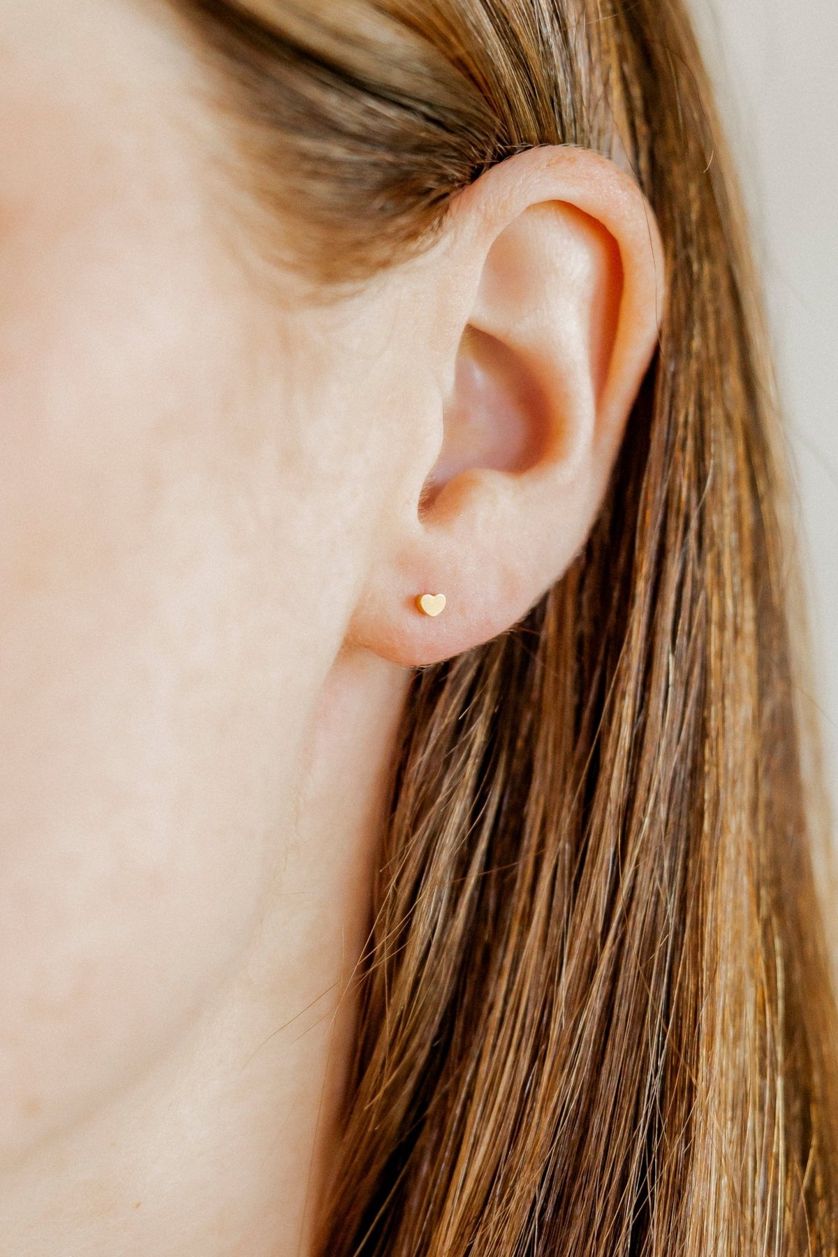 LINNY CO Micro Tessa Heart Gold screwback stud earrings for kids & little girls — hypoallergenic, waterproof stainless steel with secure screwback backs, shown on model.