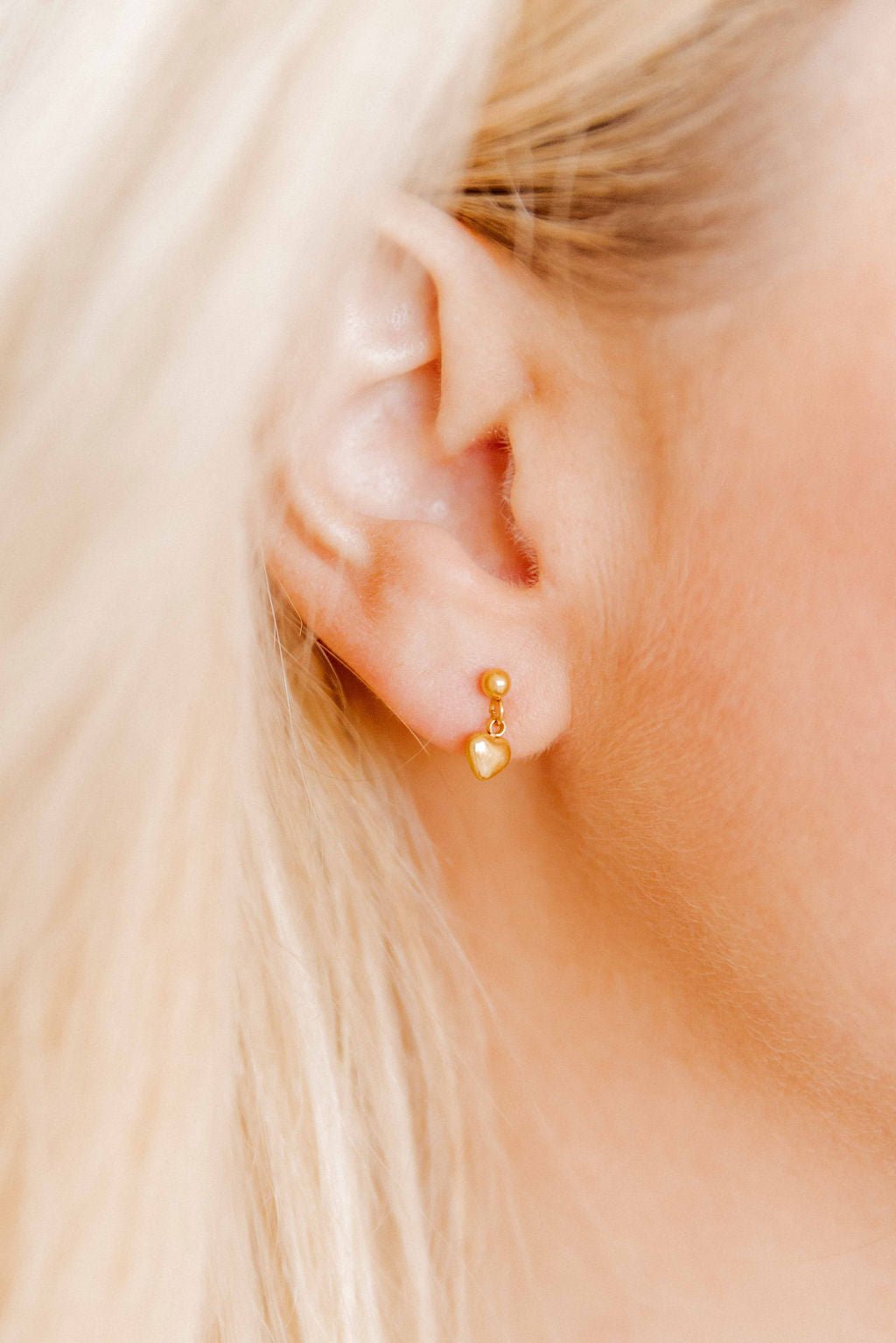 LINNY CO Millie Heart Gold screwback stud earrings for kids & little girls — hypoallergenic, waterproof stainless steel with secure screwback backs, shown on model.
