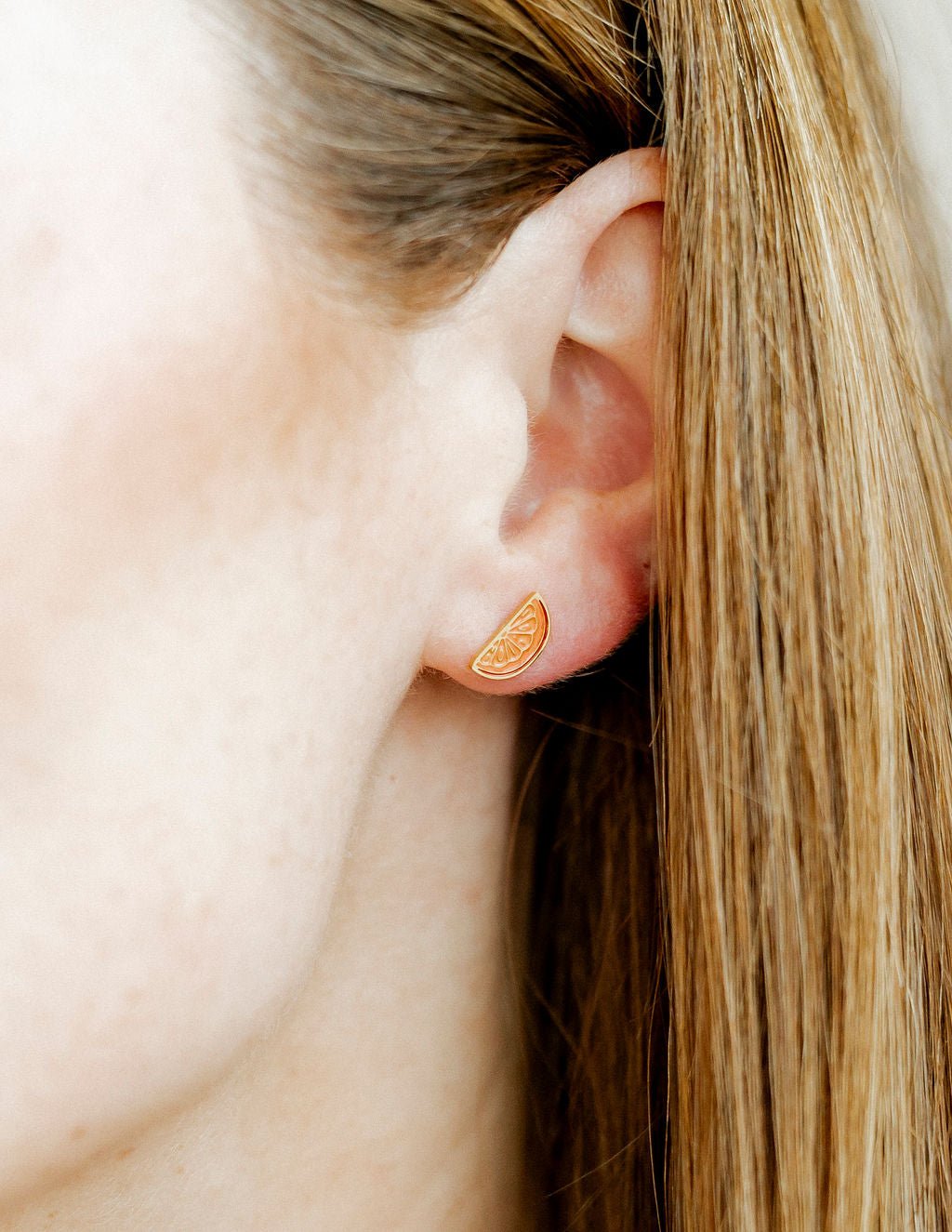 LINNY CO Orange Slice screwback stud earrings for kids & little girls — hypoallergenic, waterproof stainless steel with secure screwback backs, shown on model.