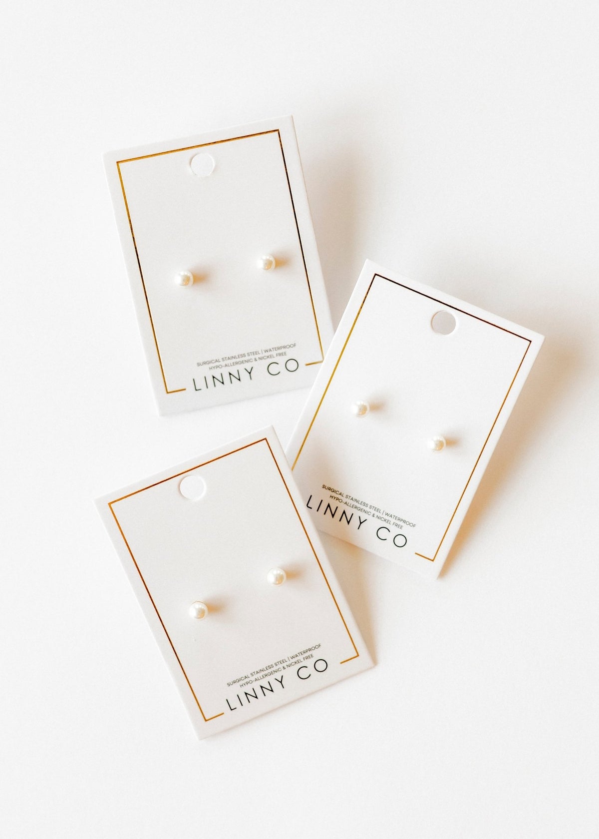 LINNY CO Payton Pearl White 5mm screwback stud earrings for kids & little girls — hypoallergenic, waterproof stainless steel with secure screwback backs, flat-lay styling.