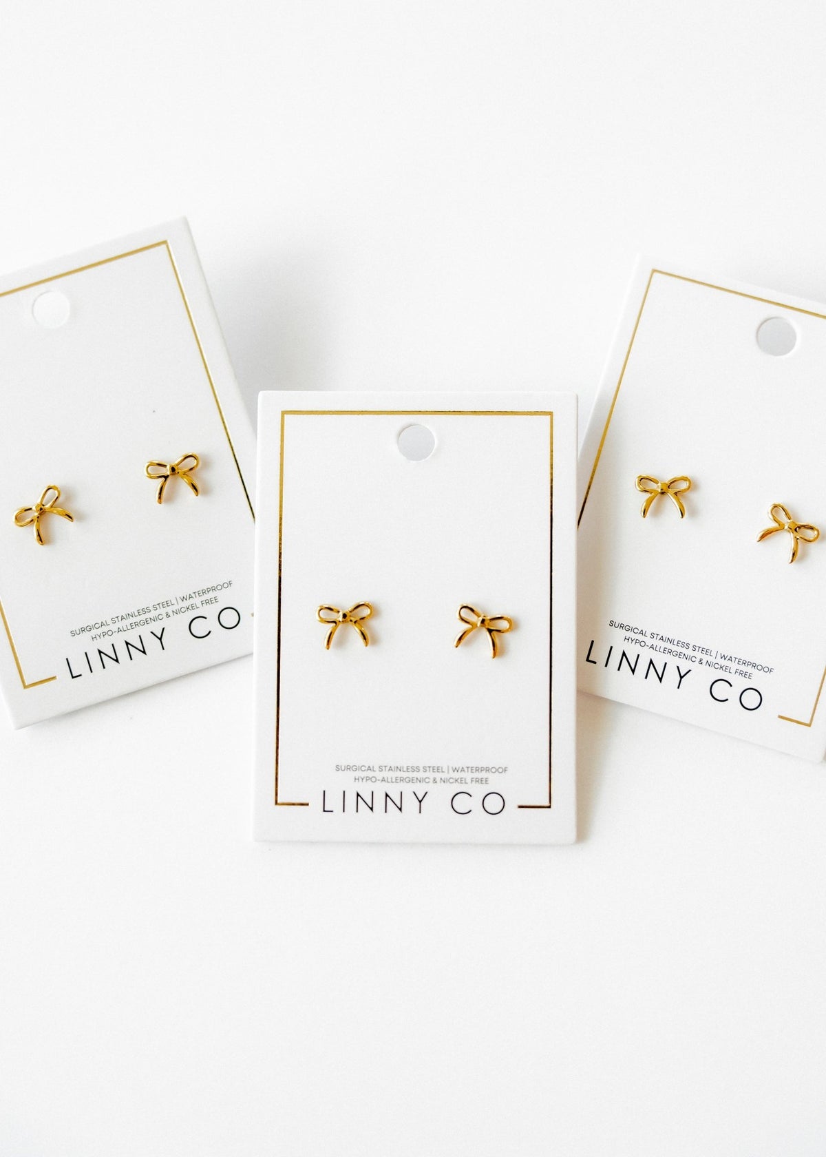 LINNY CO Sadie Bow Gold screwback stud earrings for kids & little girls — hypoallergenic, waterproof stainless steel with secure screwback backs, flat-lay styling.
