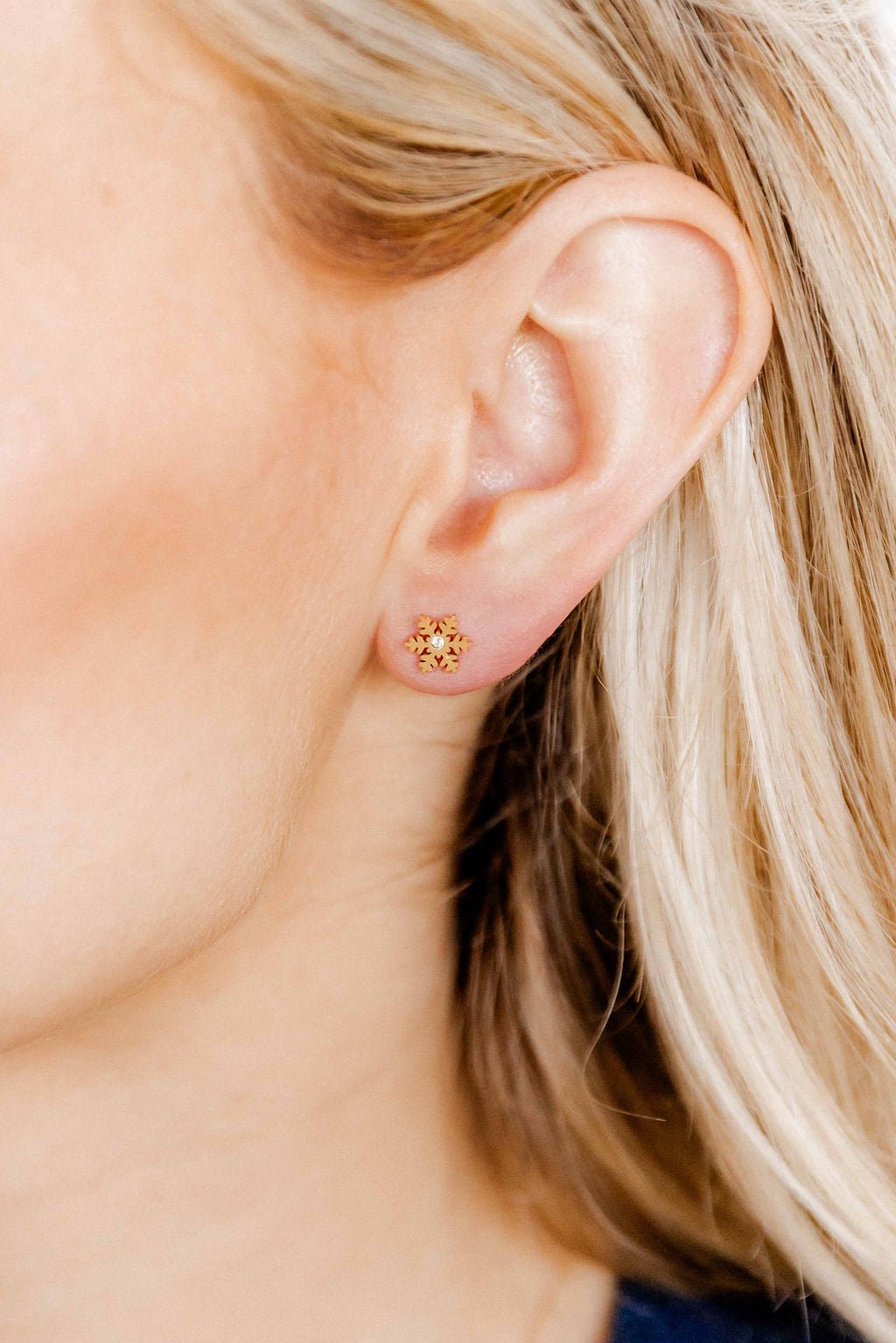 LINNY CO Snowflake Gold screwback stud earrings for kids & little girls — hypoallergenic, waterproof stainless steel with secure screwback backs, shown on model.