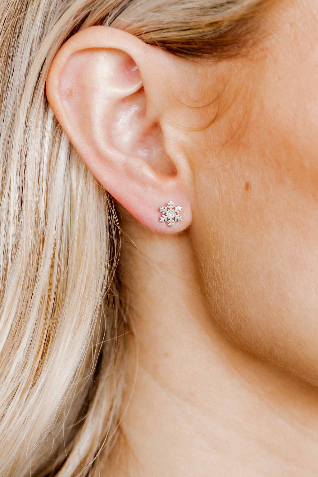 LINNY CO Snowflake Silver screwback stud earrings for kids & little girls — hypoallergenic, waterproof stainless steel with secure screwback backs, shown on model.